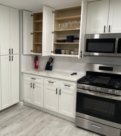 Fully stocked kitchen with stainless steel appliances, white cabinets, and marble countertops in a furnished rental home.<br />
